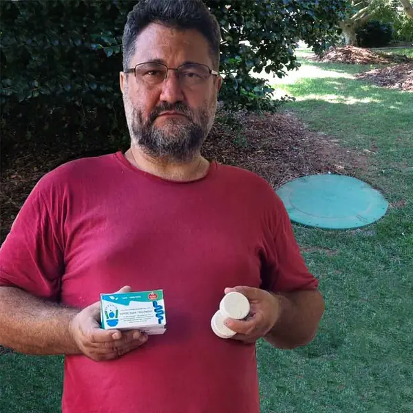 Septifix septic tank treatment tablets held next to a septic tank access cover