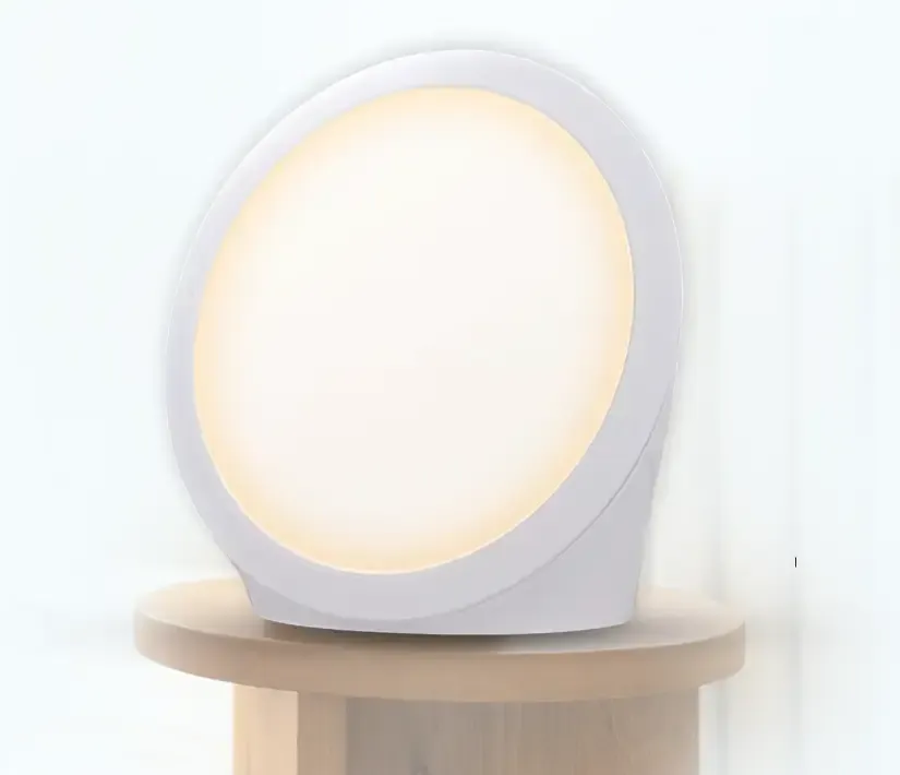 Sunniva Light daylight-simulation lamp glowing warm white on a wooden surface